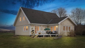 Ein zweistöckiges Haus mit einer Veranda, einer Treppe und einem Rasen.