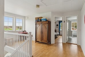 A spacious room with a wooden floor, a white railing, and a view of the outdoors.