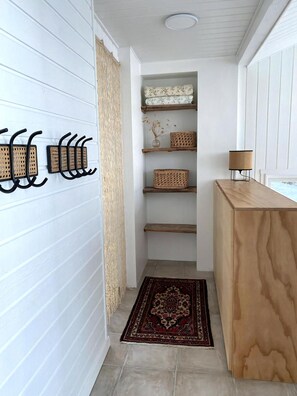 A hallway with a wooden reception desk, a patterned rug, and a wall-mounted rack with hooks.