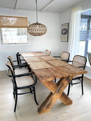 A dining table with woven placemats, black metal chairs, and a woven pendant light.