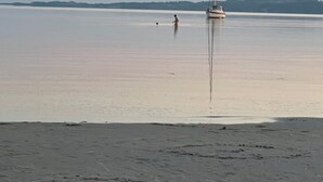 Tyyni vesialue, jossa on purjevene ja kauempana näkyy henkilö.