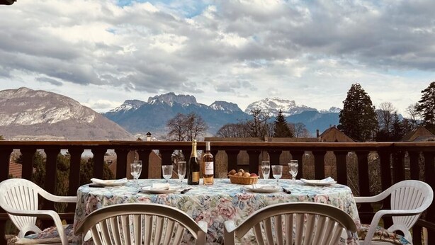 Un área de comedor al aire libre con una mesa dispuesta para dos, con vistas a un paisaje montañoso.