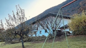 Un área verde con un columpio y una casa al fondo.