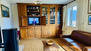 Una sala de estar con un aparador de madera, un televisor, un sofá de cuero marrón y un suelo con estampado.