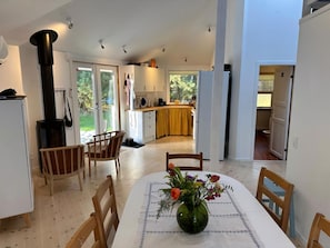 Une cuisine moderne avec des meubles blancs, une cuisinière noire et un coin repas avec une table dressée pour deux personnes.