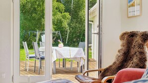 Een kamer met een grote glazen deur die uitkomt op een terras met een tafel en stoelen.