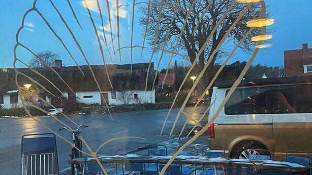 An outdoor seating area with chairs and tables, a metal sculpture, and a parked vehicle.