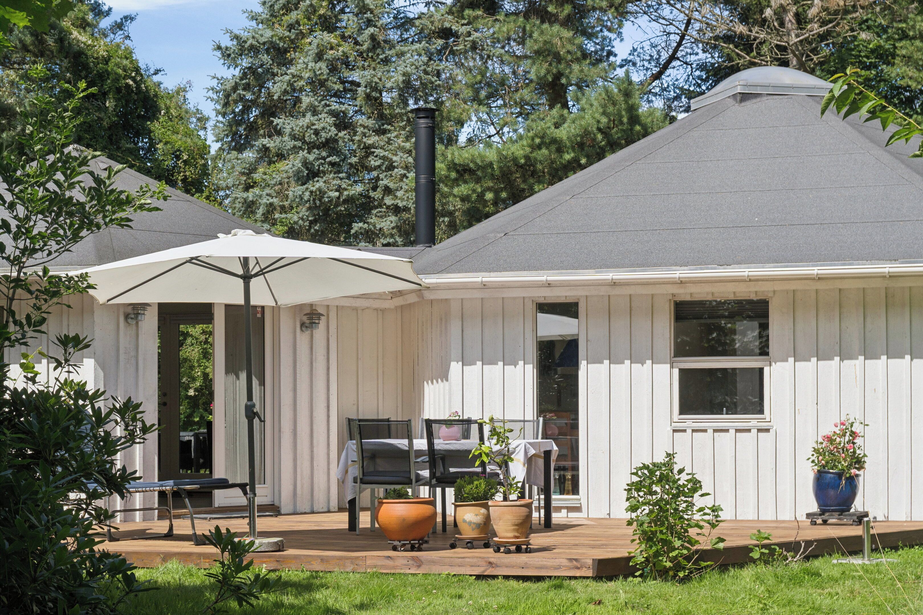 A house with a covered patio, outdoor furniture, and potted plants.