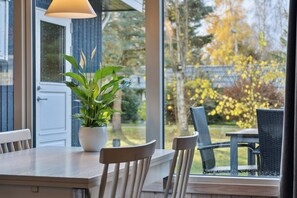 Een eethoek met een tafel, stoelen, een potplant en uitzicht op het buiten.