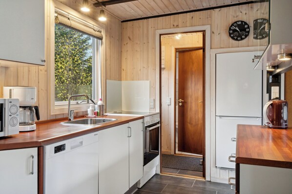 Eine moderne Küche mit Holzwänden, einem Spülbecken, einem Herd und einem Kühlschrank.