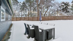 A snow-covered patio with outdoor furniture and a wooden fence. - Cozy beach bungalow close to Balka Beach (Nexø)