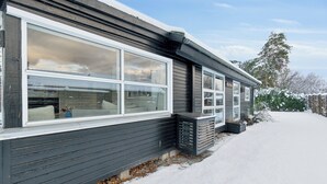 A modern house with large windows, a dark exterior, and a snow-covered driveway. - Cozy beach bungalow close to Balka Beach (Nexø)