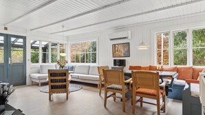 Una habitación amplia con una mesa de comedor, sillas, un sofá y un televisor.