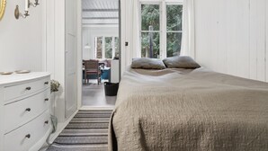 Un dormitorio con cama, cómoda, ventana y puerta que da a otra habitación.