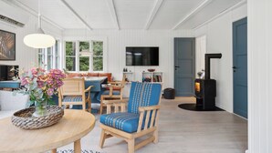 Una sala de estar con televisor, chimenea y comedor con mesa y sillas.