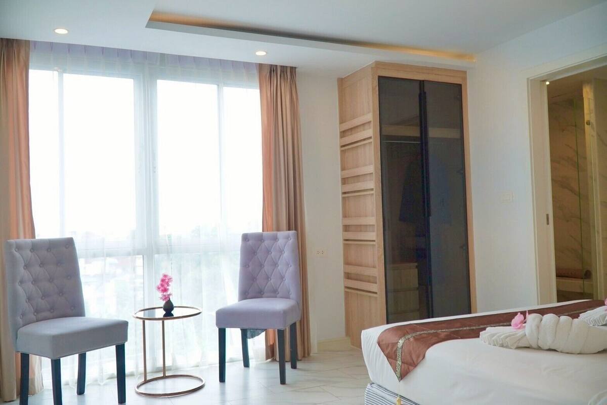 A hotel room with a bed, two armchairs, a small table, and a wardrobe.