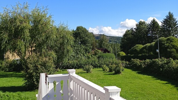 A wooden deck with white railings overlooking a well-maintained lawn and trees. - Holiday Home Bispgården (Bispgården)