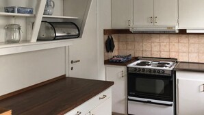 A kitchen with white cabinets, a stove, and a microwave. - Holiday Home Bispgården (Bispgården)