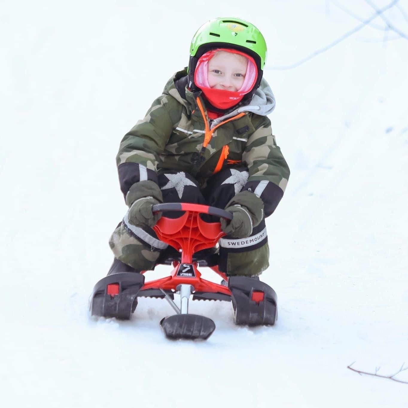 A child on a snowmobile in a snowy environment.