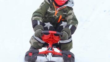 A child on a snowmobile in a snowy environment.