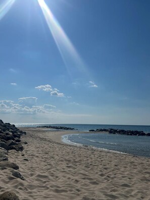 A beach with clear skies, a sandy shore, and a calm sea.