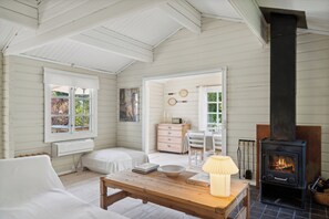 A cozy room with a fireplace, a wooden table, a white sofa, and a window with curtains.