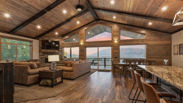 Un amplio salón con chimenea, asientos cómodos y grandes ventanales con vistas a la montaña.