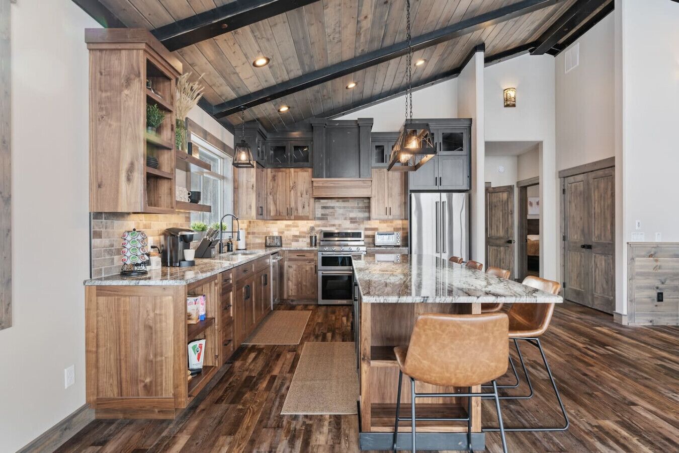 A spacious kitchen with wooden cabinets, a marble countertop, and a central island with bar stools.