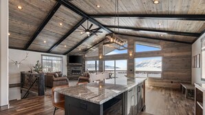 Una cocina amplia con una isla grande, pisos de madera y un techo alto con vigas a la vista.