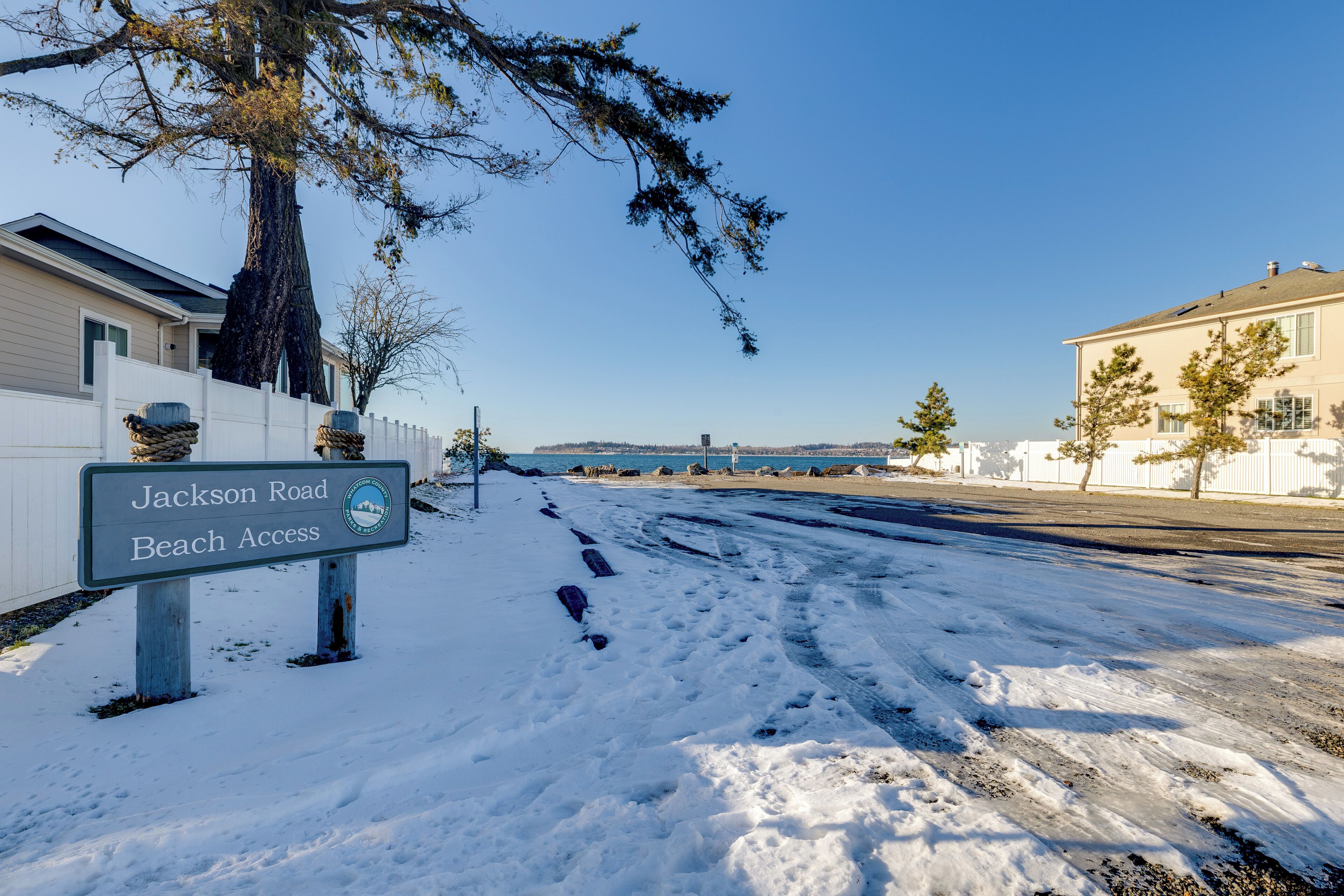 A snow-covered road with a sign indicating Jackson Road Beach Access.