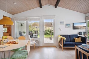 A modern interior with a dining area, a sofa, and a view of the garden. - Cozy and calm - close to beach and great terraces (Slagelse)