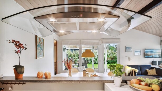 Une cuisine moderne dotée d’un îlot central, d’un coin repas avec une table et d’une vue sur l’extérieur.