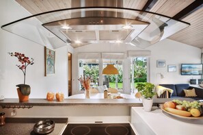 Une cuisine moderne dotée d’un îlot central, d’un coin repas avec une table et d’une vue sur l’extérieur.