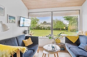 A modern living room with a large window, a sofa, a coffee table, and a lamp.