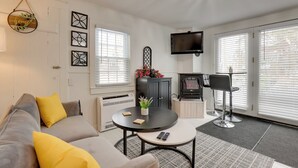 Un salon moderne avec un canapé, une table basse ronde, une cheminée et un téléviseur fixé au mur.