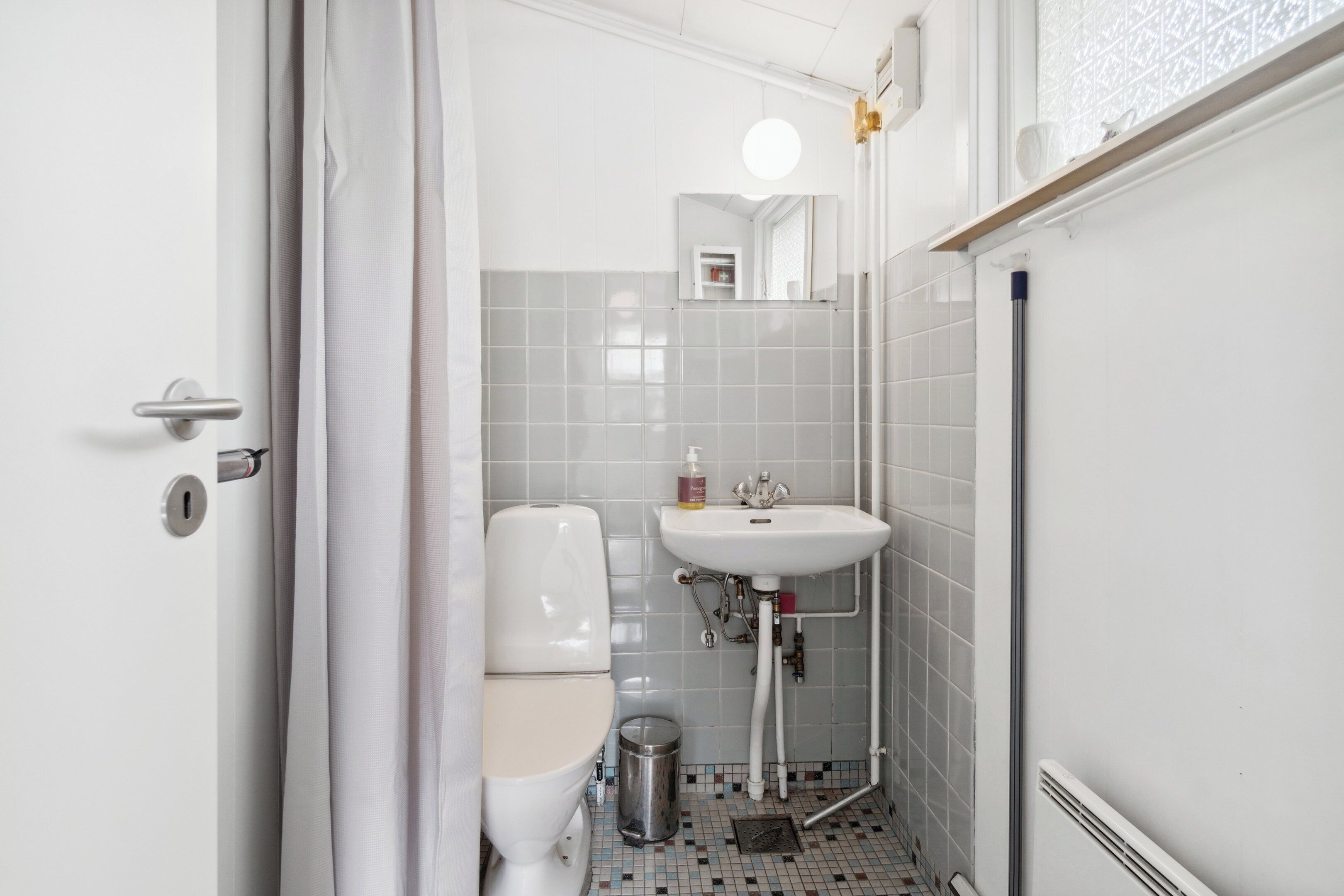 A small bathroom with a toilet, sink, and mirror.
