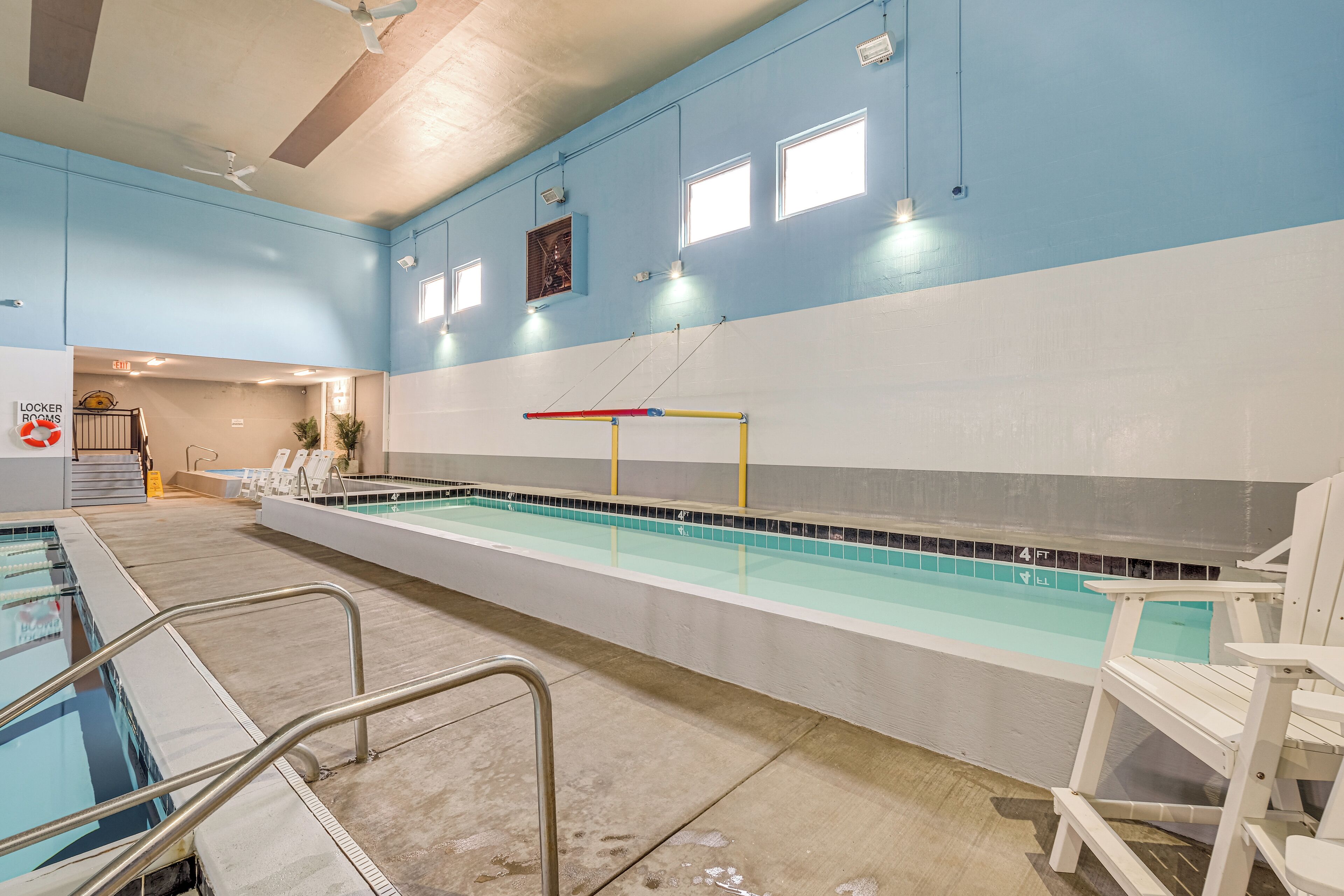 Zona de piscina con trampolín, sillas de descanso y letrero de vestuario.