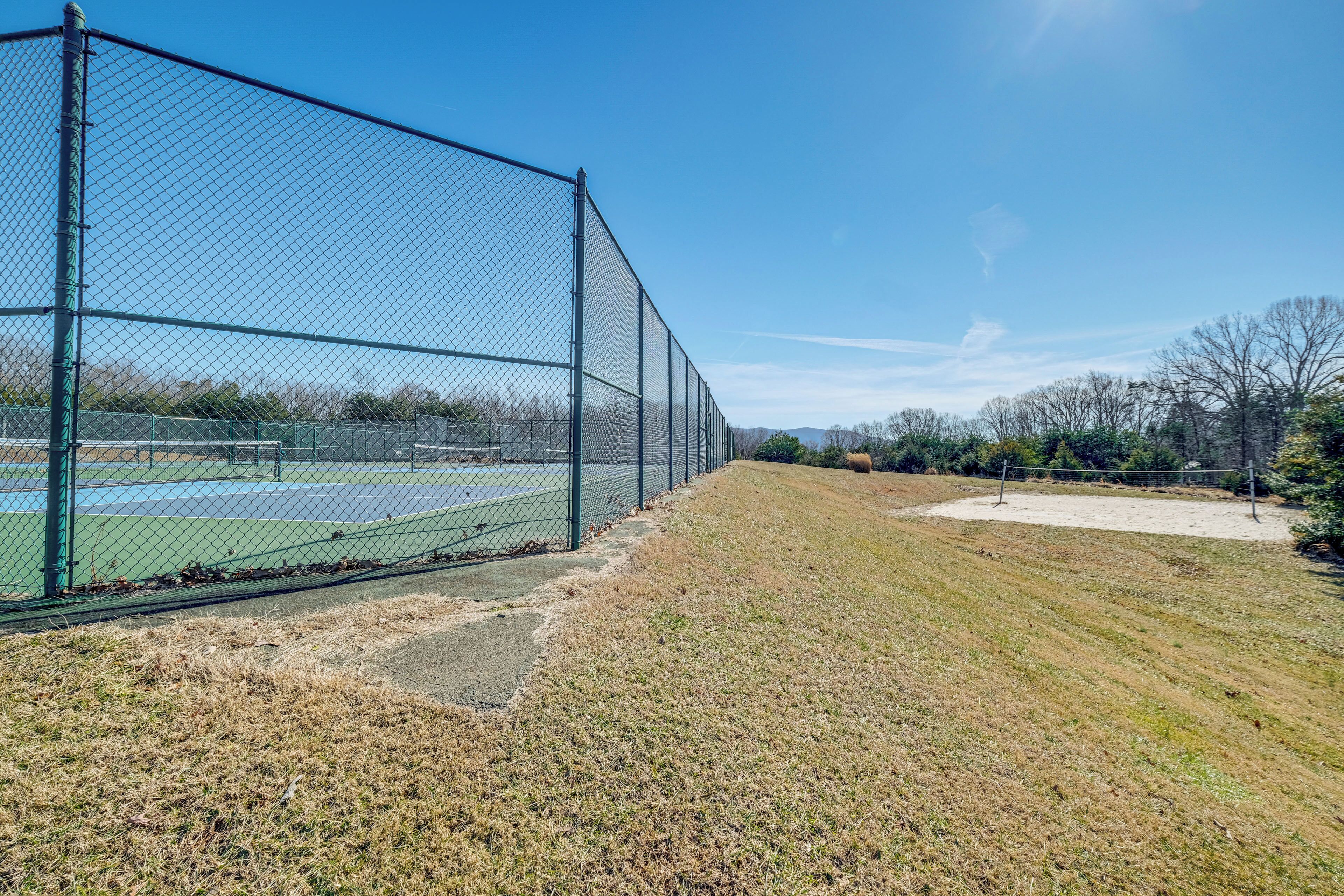 A fenced tennis court with a clear sky.