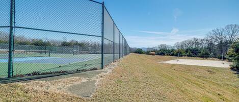 A fenced tennis court with a clear sky.