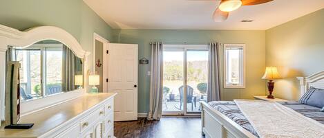 A bedroom with a bed, a dresser, a ceiling fan, and a view through a glass door to an outdoor patio.