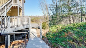 A wooden staircase leading to a porch with a view of a forested area. - 'better Lake Than Never' Huddleston Condo (Huddleston)