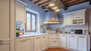 Una cocina con muebles blancos, horno empotrado y ventana.