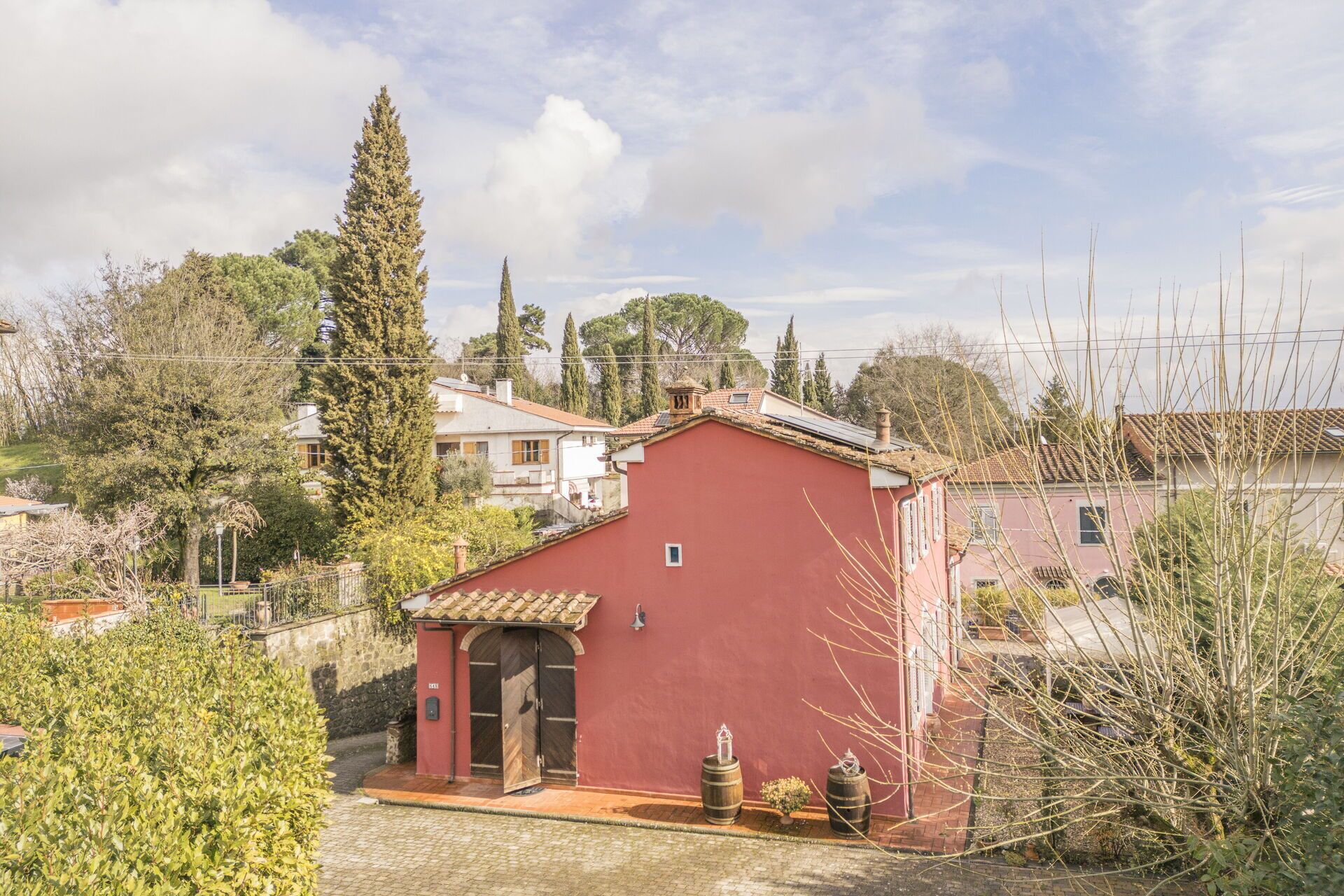 A red building with a small entrance and two barrels outside.