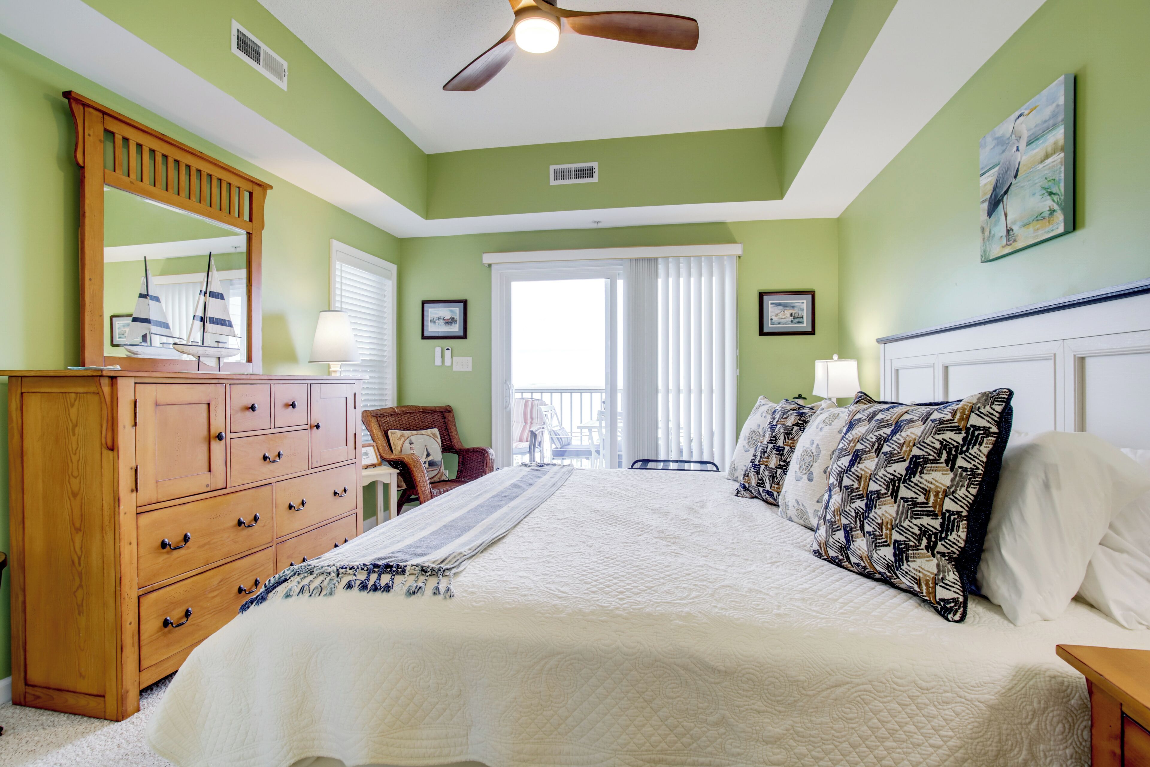 A bedroom with a large bed, wooden dresser, and a ceiling fan.