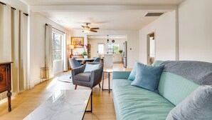A spacious living room with a large sofa, a coffee table, and a dining area with chairs and a table. - Updated Home w/ Private Deck, 1 Mi to Rose Bowl! (Pasadena)