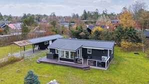 A modern house with a large deck, a covered patio, and a well-maintained lawn. - Holiday idyll near beach and city life (Hals)