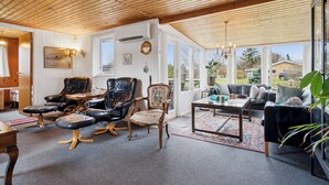 A spacious living area with a wooden ceiling, leather chairs, a sofa, and a dining table. - Holiday idyll near beach and city life (Hals)