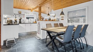 A modern kitchen with a wooden ceiling, a dining area with a table and chairs, and a large window with a cityscape view. - Holiday idyll near beach and city life (Hals)