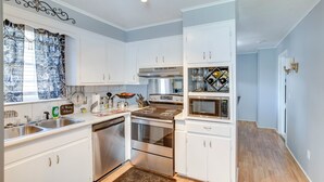 Una cocina moderna con armarios blancos, electrodomésticos de acero inoxidable y suelo de madera.