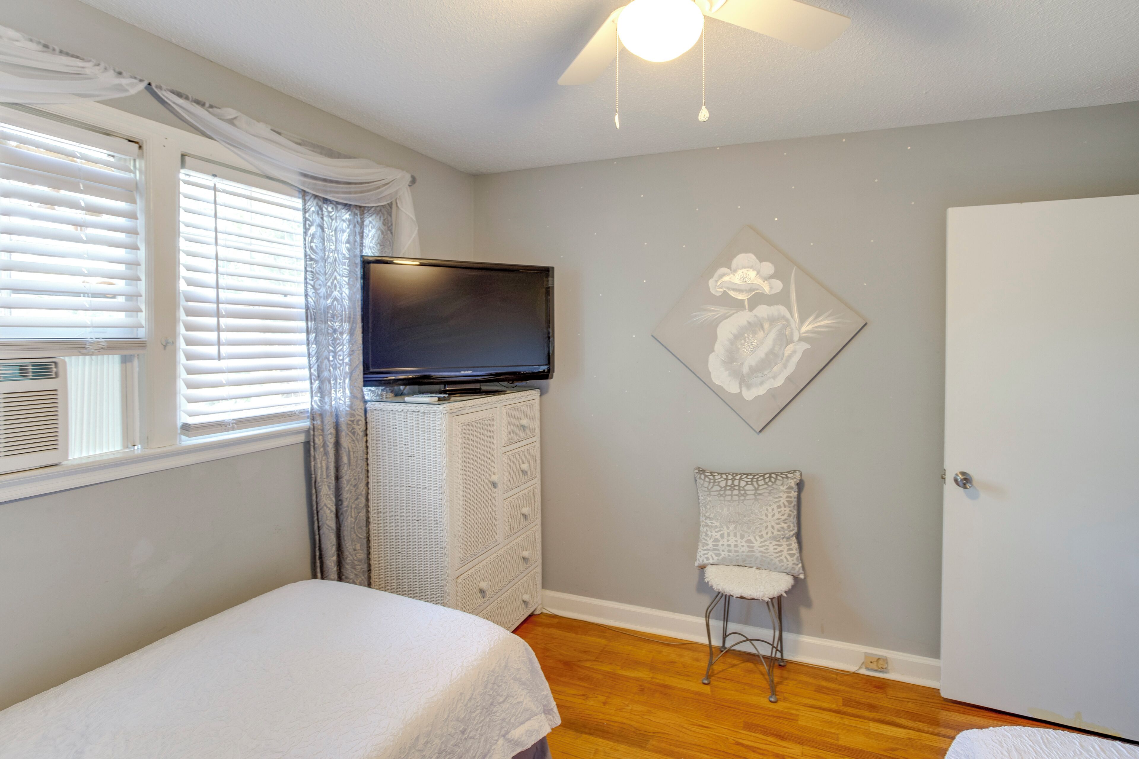 A bedroom with a bed, a dresser, a television, a chair, and a door.